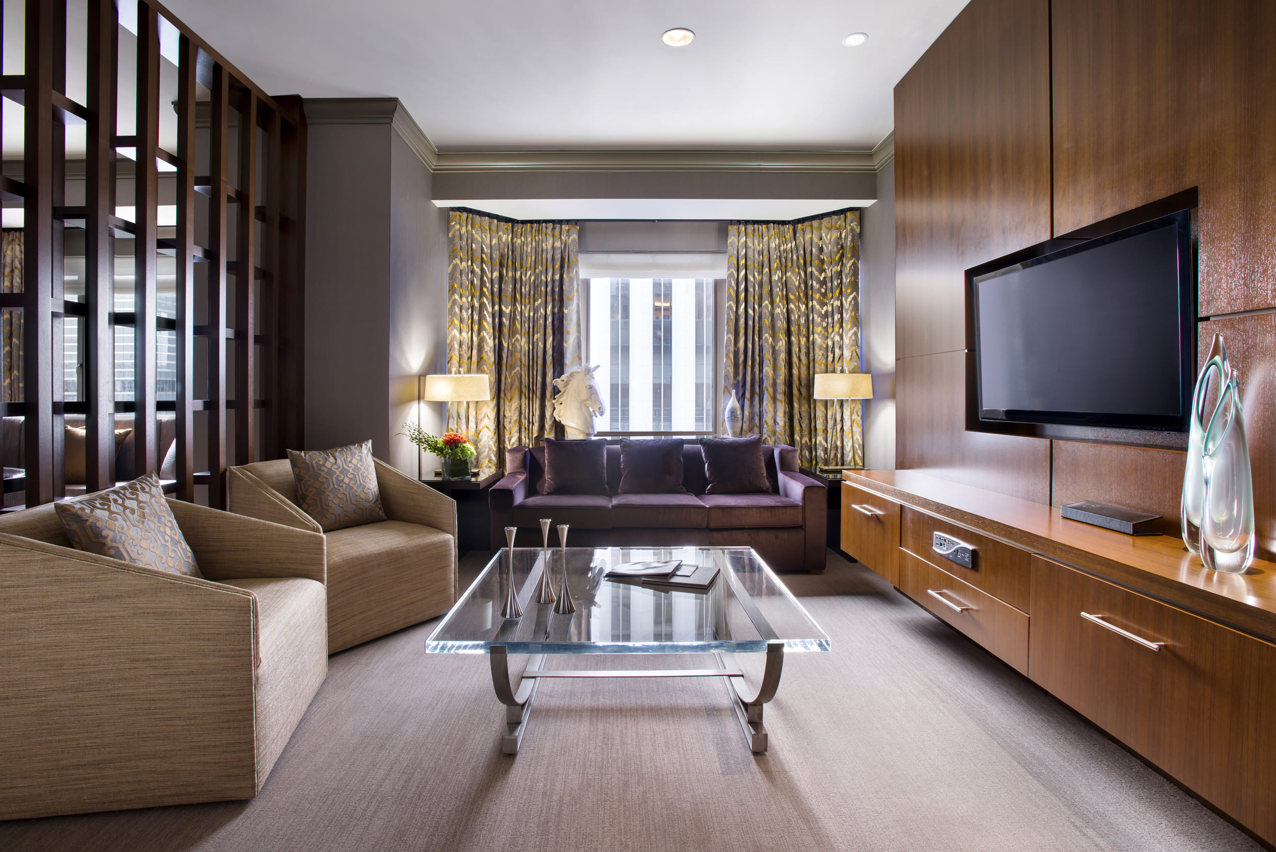 large living room with a purple couch, two beige chairs and a tv
