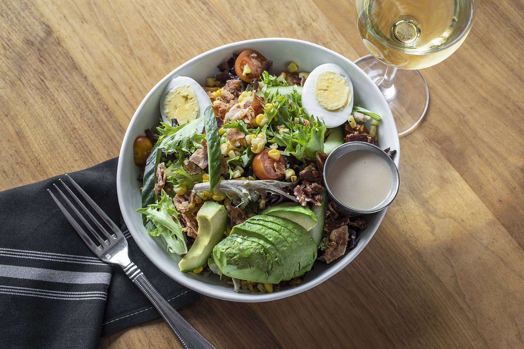 large salad with hard boiled eggs, avocado, bacon and other vegetables