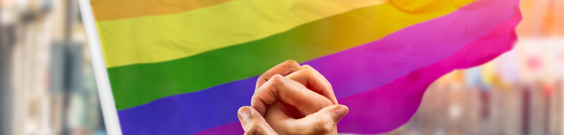 Hands holding in front of pride flag