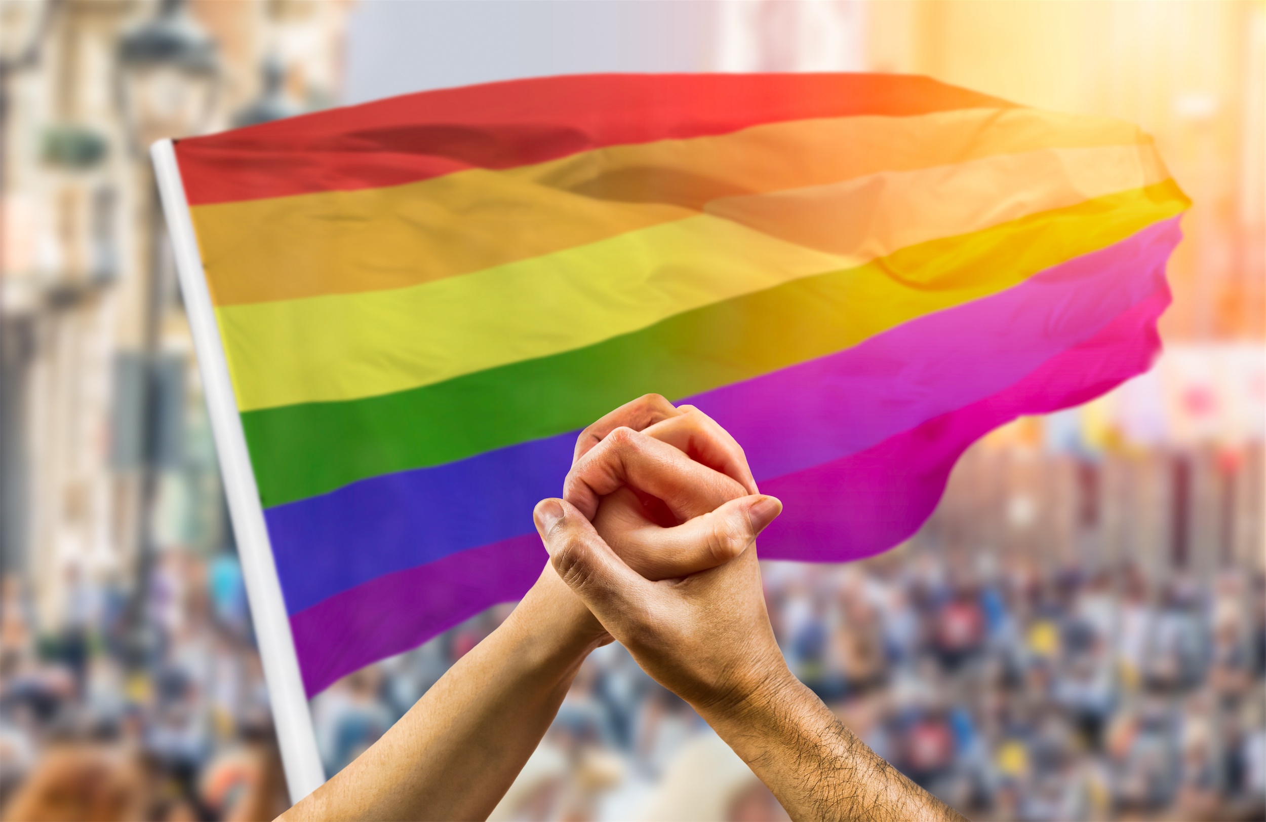 Hands holding in front of pride flag